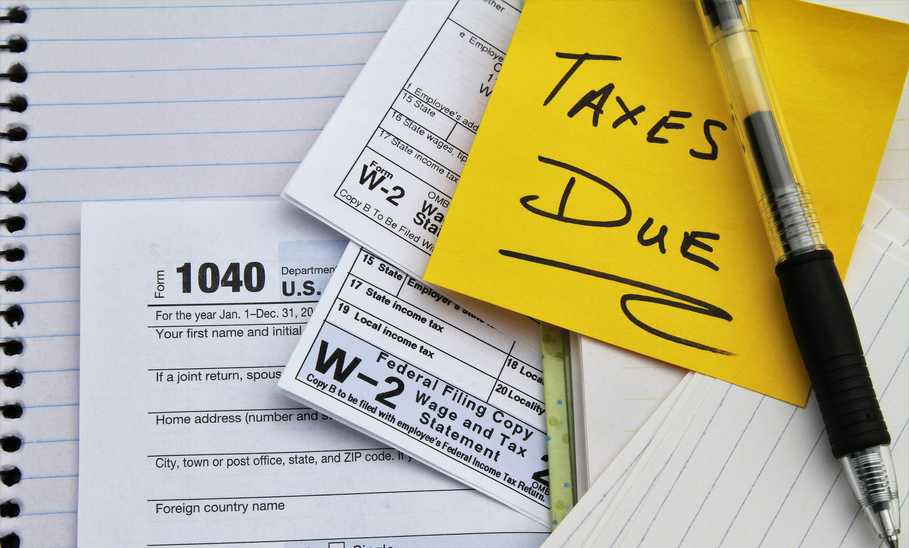 Tax return forms and wage statements with note Taxes Due